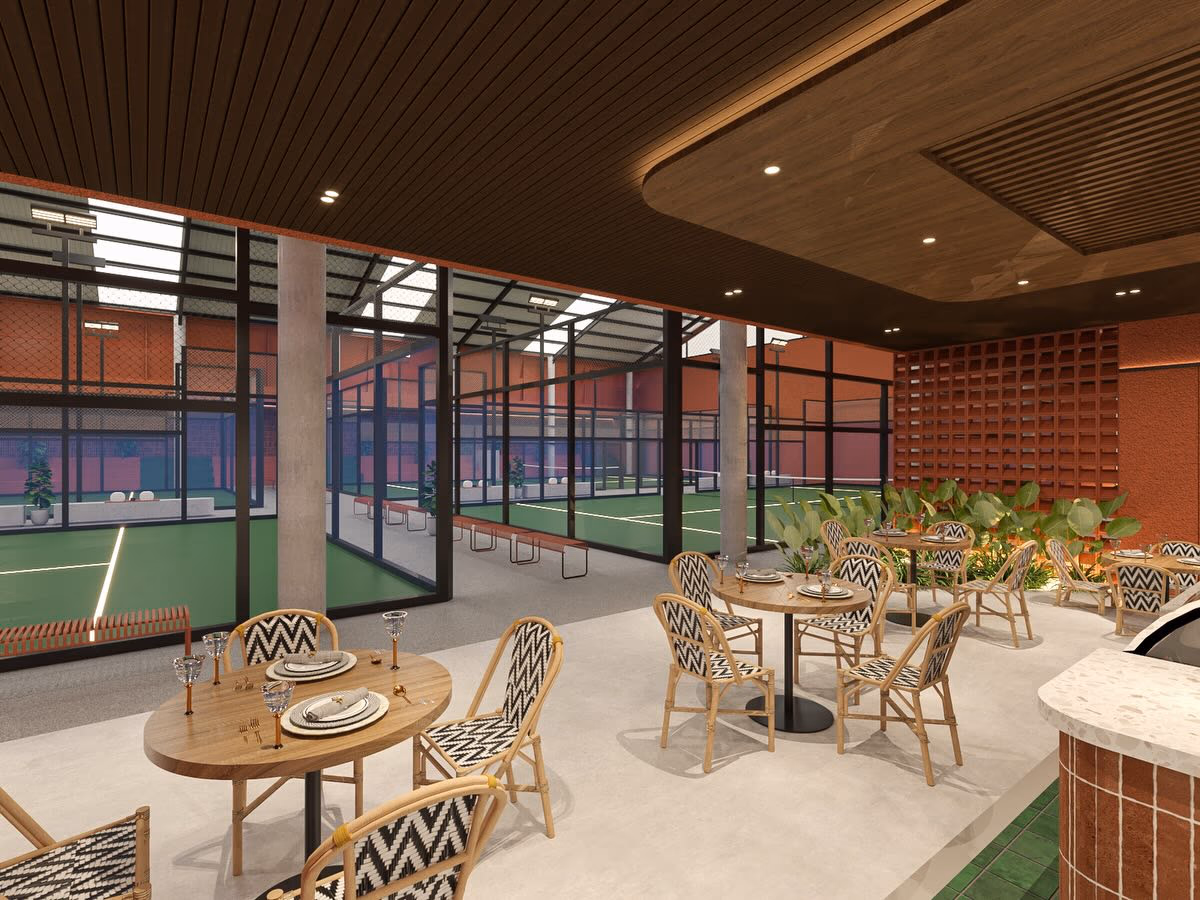 Café tables set directly against the court glazing, every seat looking down a playing surface