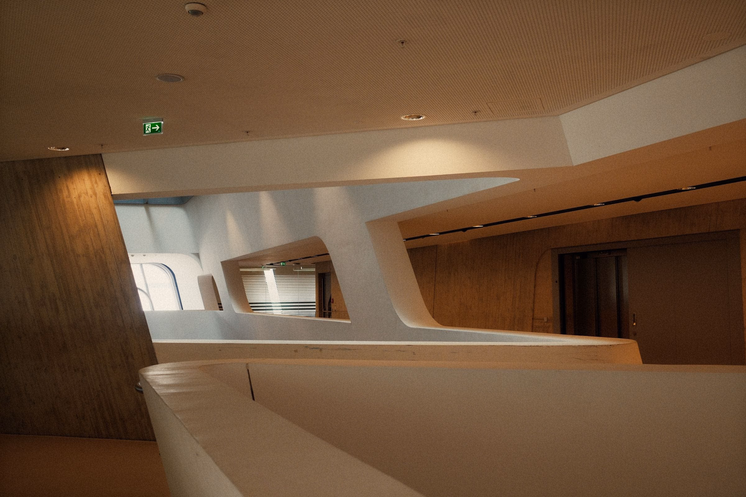 A curved white volume turning into a timber wall, the junction left uninterrupted